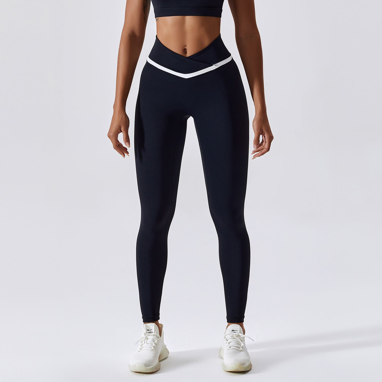 Woman wearing black leggings and a black sports bra on a white background