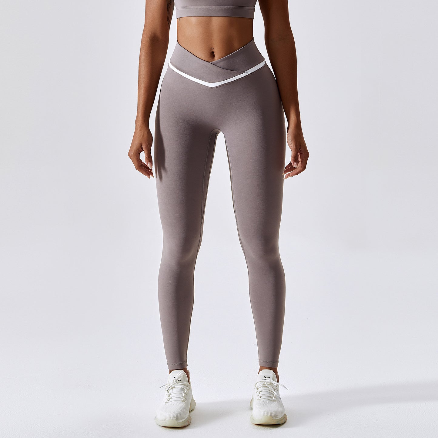 Woman wearing light purple leggings with a white waistband on a light gray background