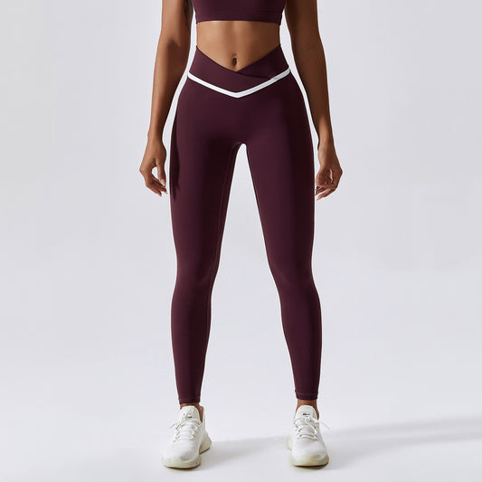 Woman wearing maroon leggings with a white waistband on a light gray background